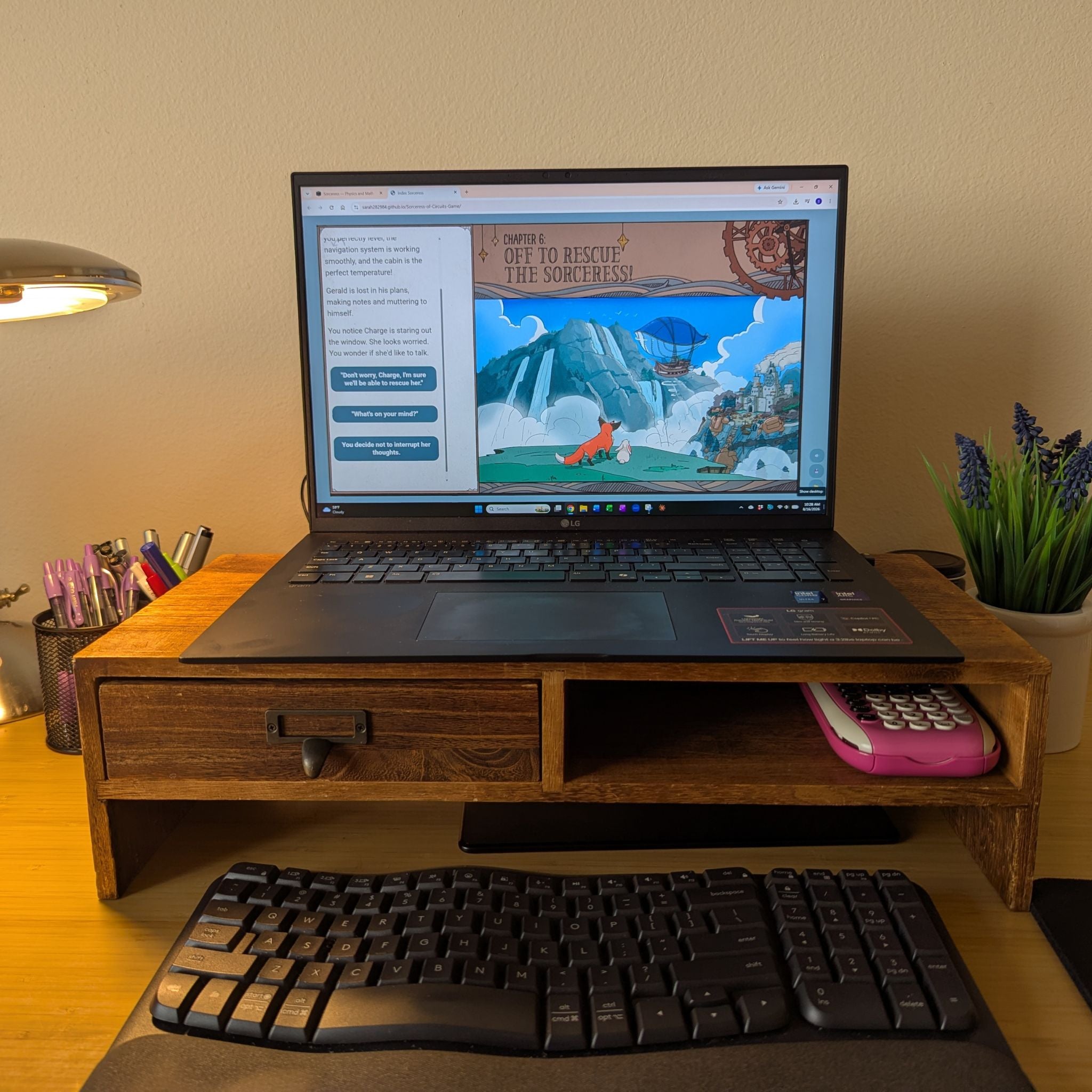 A wooden desktop riser holding an open laptop on a desk, with a keyboard in front and a small pink calculator in the shelf. the game on the screen reads 'Chapter 6: Off to rescue the sorceress!' and has a cute illustration of a fox and a zeppelin