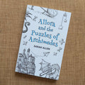 the paperback of Allora sitting on fabric