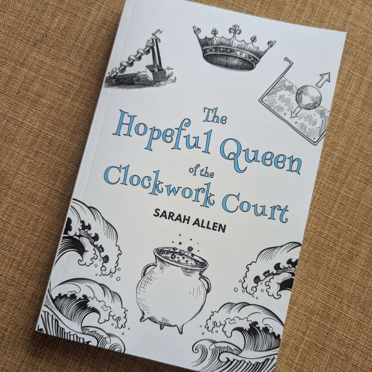 The book The Hopeful Queen of the Clockwork Court sitting on some fabric