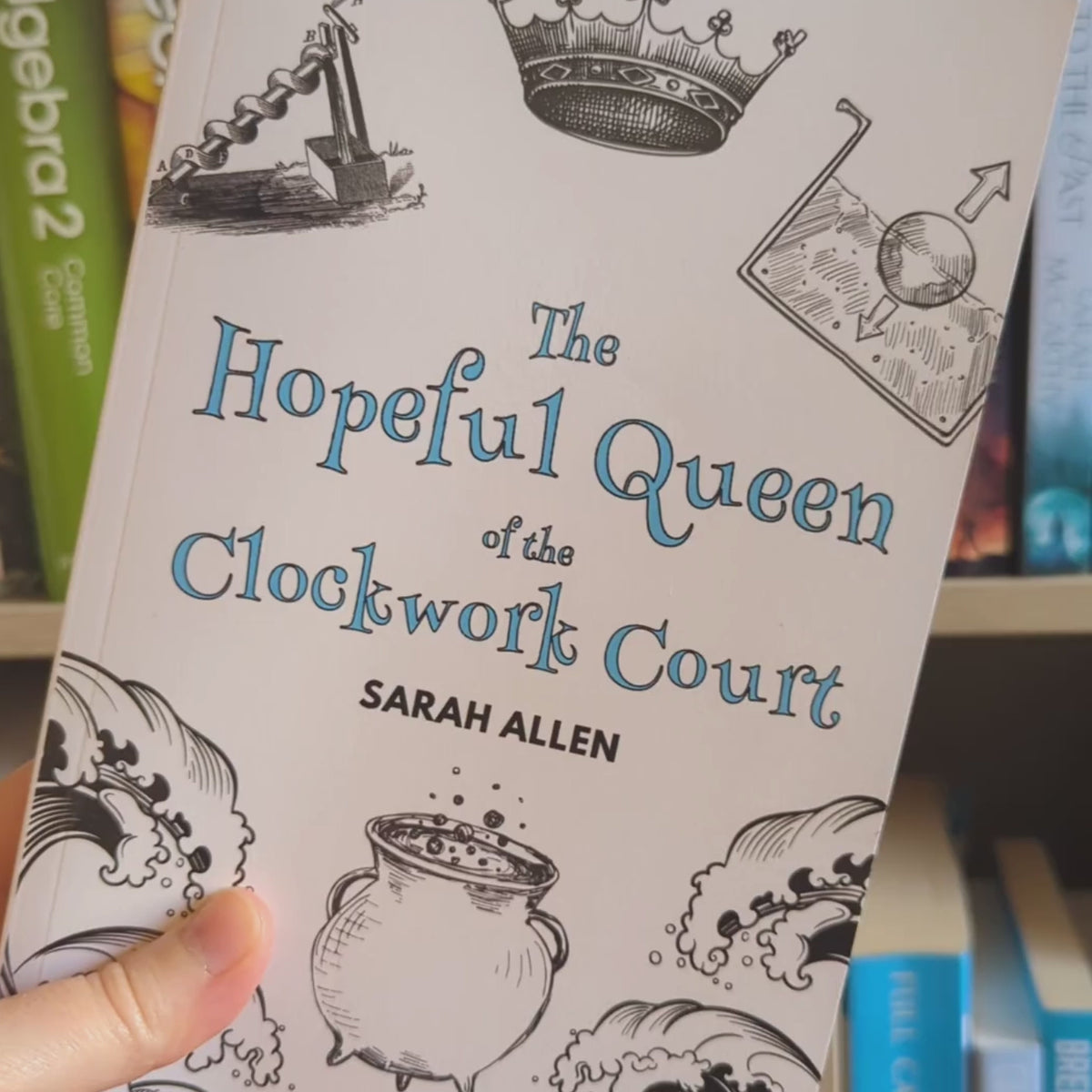 A video of the Hopeful Queen of the Clockwork Court book being rotated in front of a bookshelf. The spine is about 2/3 of an inch thick